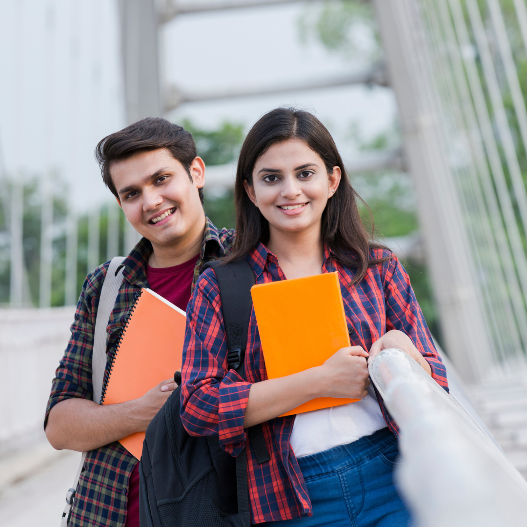 Two students carrying books on a college campus